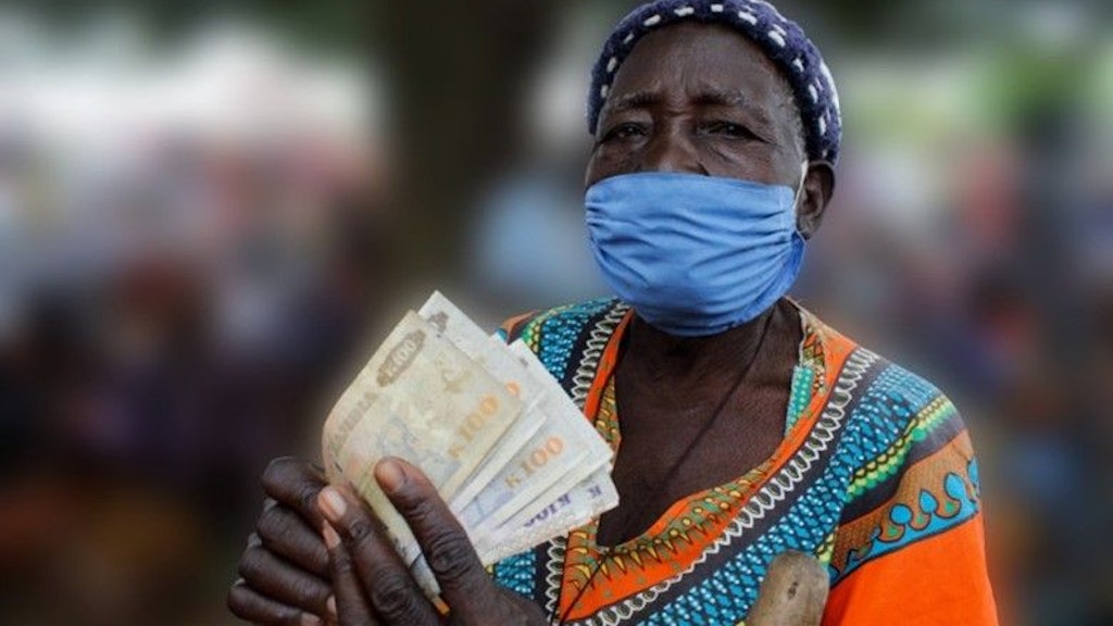 Woman wearing a face mask holding multiple bills of currency in her hands