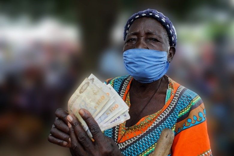 Woman wearing a face mask holding multiple bills of currency in her hands