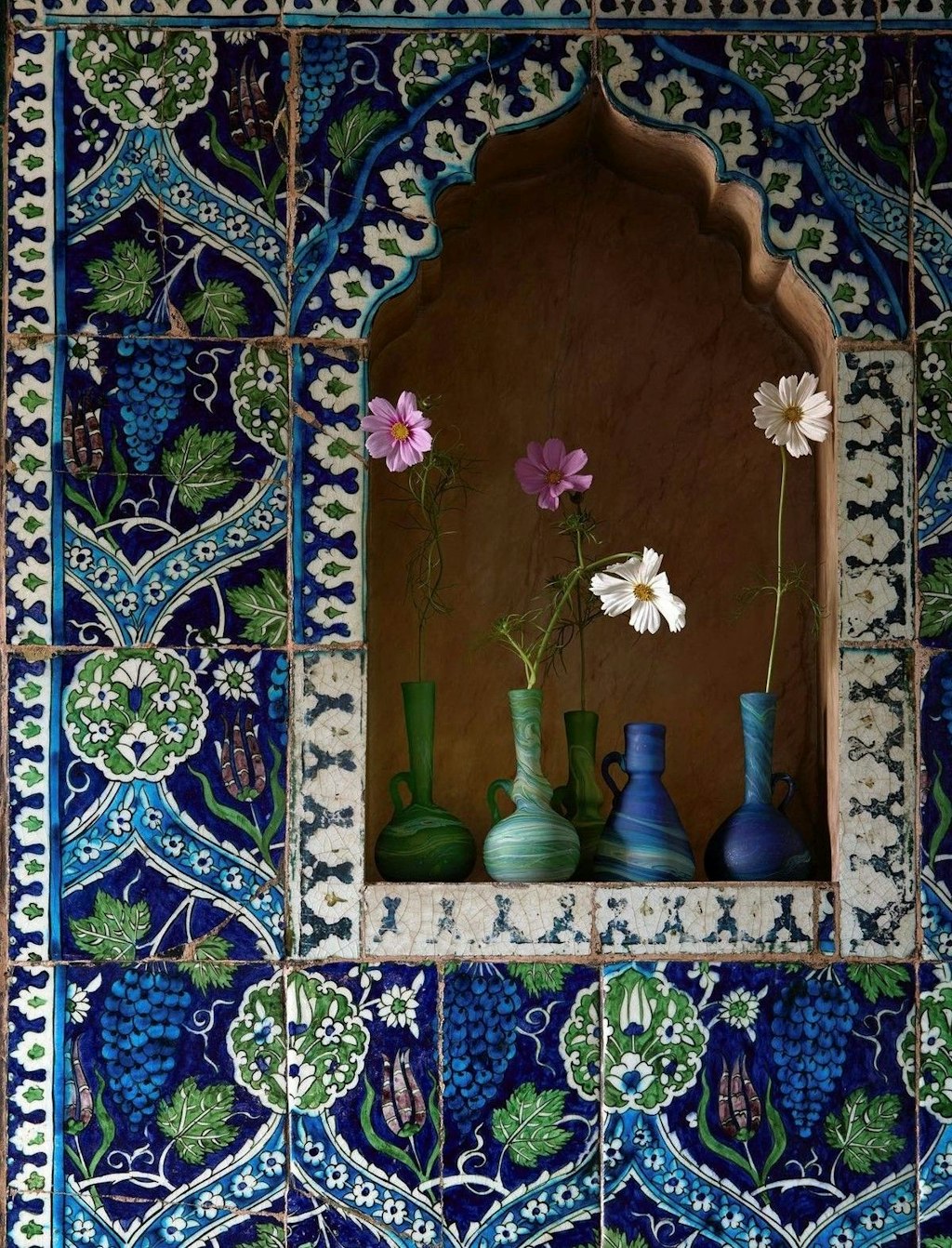 A window in the wall with Arabic ornaments and clay vases with flowers